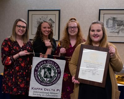 Four founding members of Kappa Delta Pi hold chapter banner and document